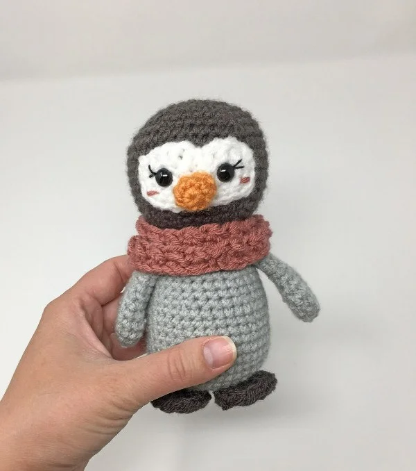 A mini crochet penguin with a pink scarf.