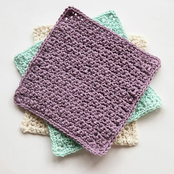 Three crochet washcloths layered together.