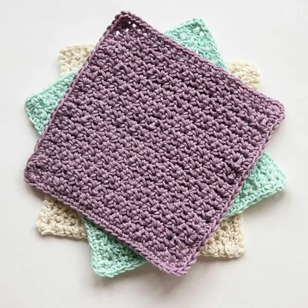 Three crochet washcloths layered together.