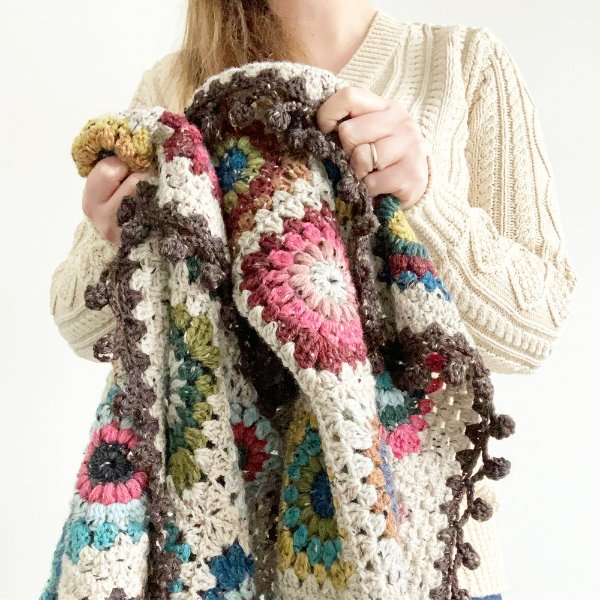 A granny squate blanket with a pompom border.