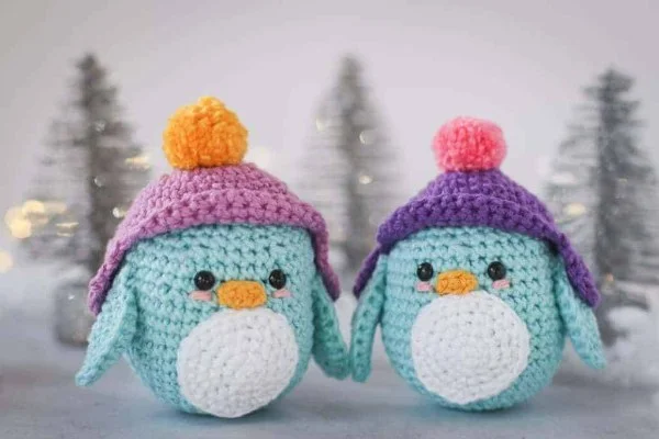 Two mini crochet penguins with beanie hats.