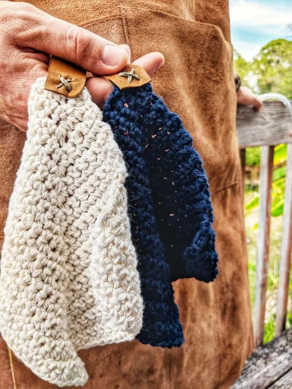 Two mitred crochet square washcloths with leather loops.