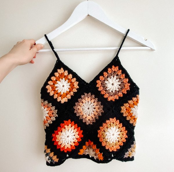 A colourful granny square top made in fall colours with contrasting black edging.