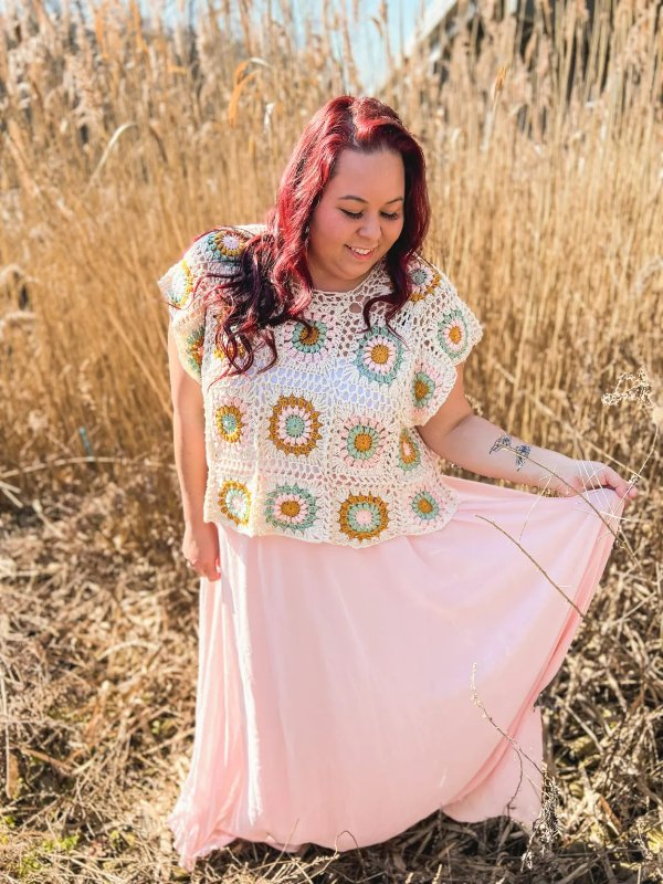 A woman wearing a summer granny square top with a long pink skirt.