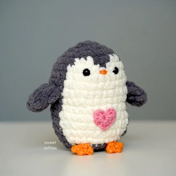 A black and white crochet penguin with an applique heart on his belly.