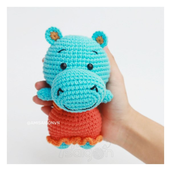 A bright blue crochet hippo in a dress.