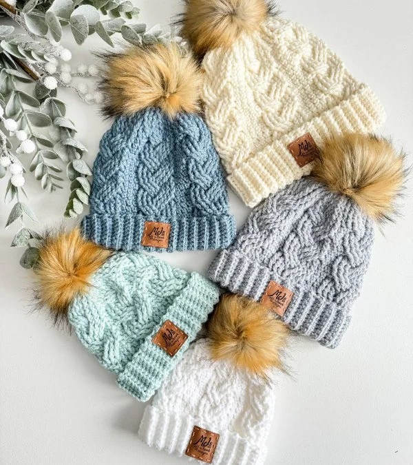 Five cable crochet hats in different colours.