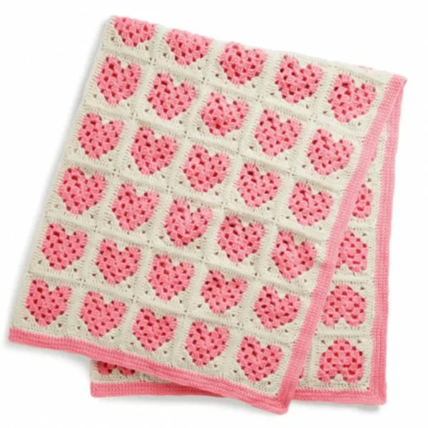 A pink and white baby blanket with heart-motif granny squares.