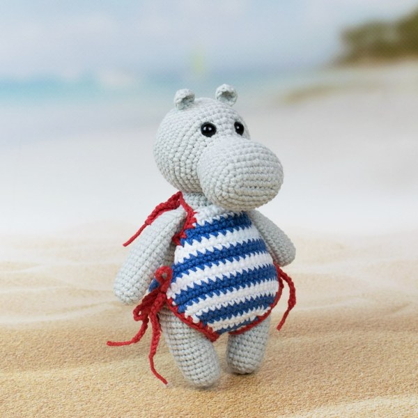 A small amigurumi hippopotamus in a striped swimsuit.