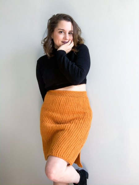A woman wearing an orange crochet pencil skirt.
