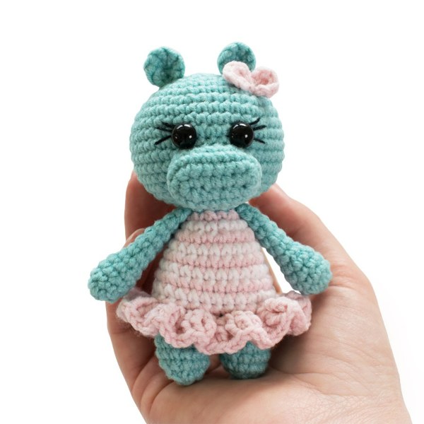 A tiny crochet hippo in a frilly dress.