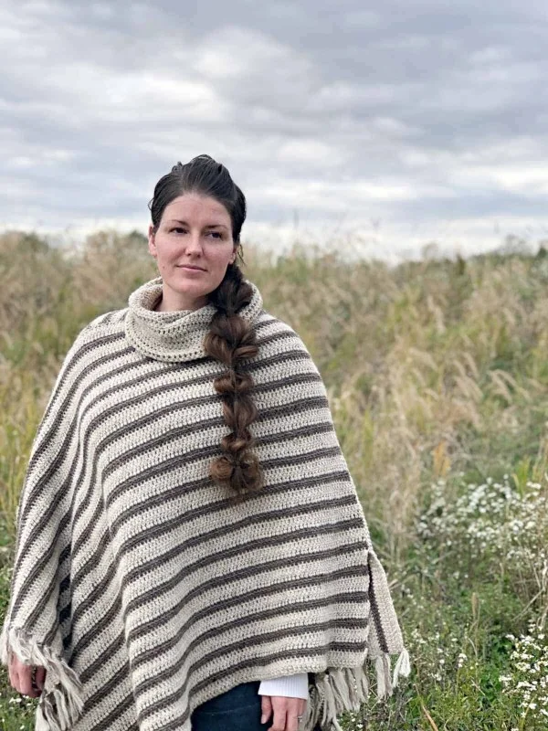 A woman wearing a striped, assymetrical crochet poncho.