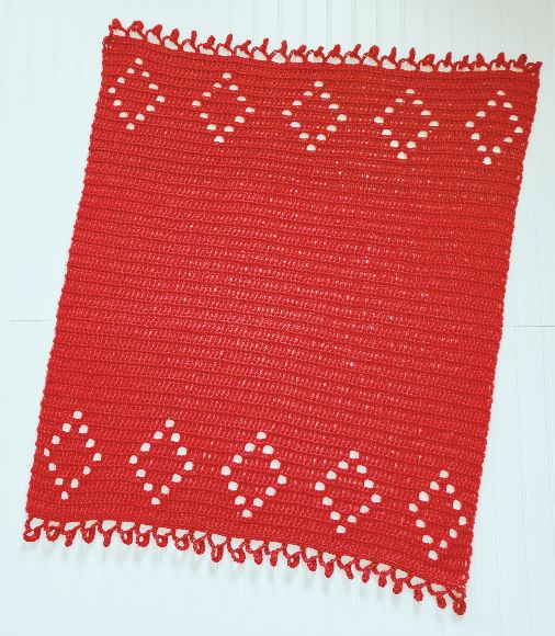 A red crochet blanket with filet crochet diamonds.