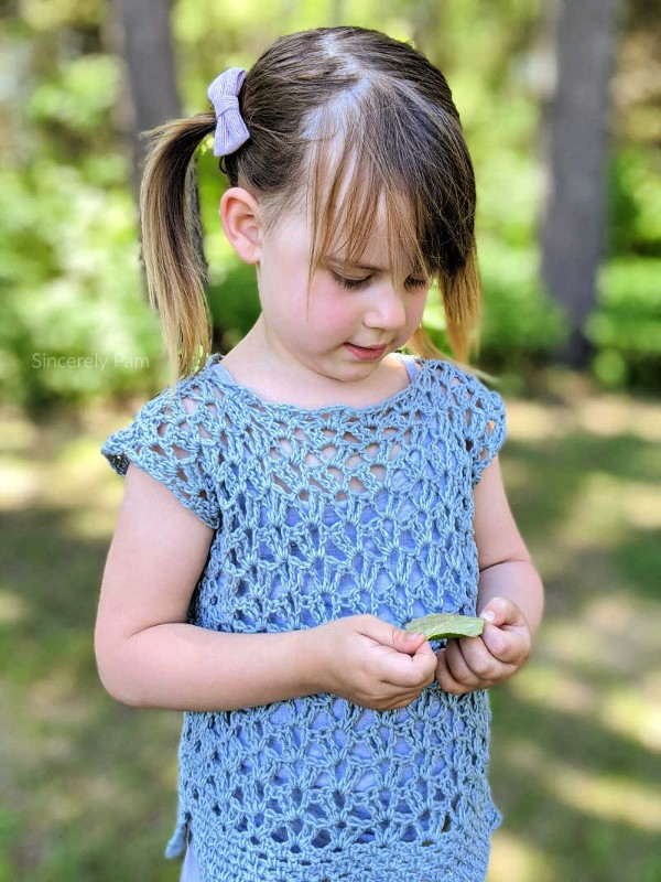 A girl wearing a lacy blue crochet top.