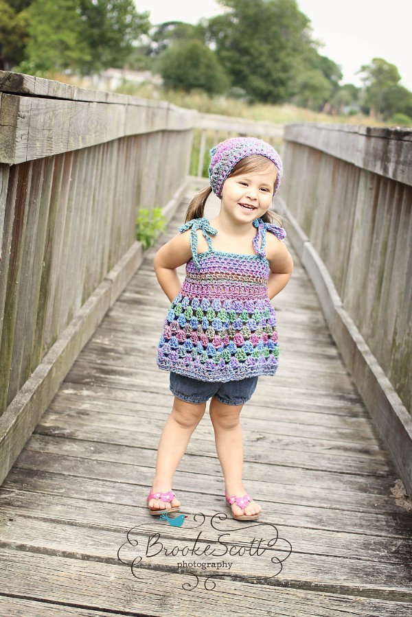 A young girl wearing a crochet top with tie straps.