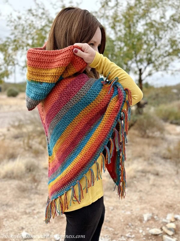 A brightly coloured hooded crochet poncho.