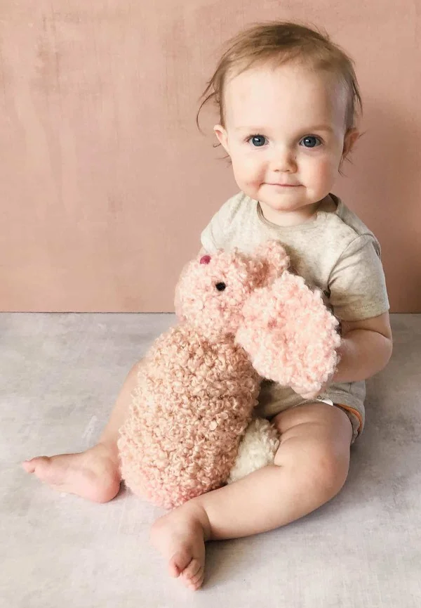 A baby holding a crochet bunny toy.
