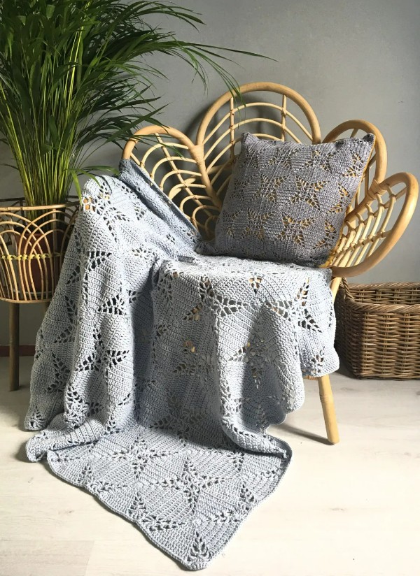 A filet crochet blanket on a cane chair.