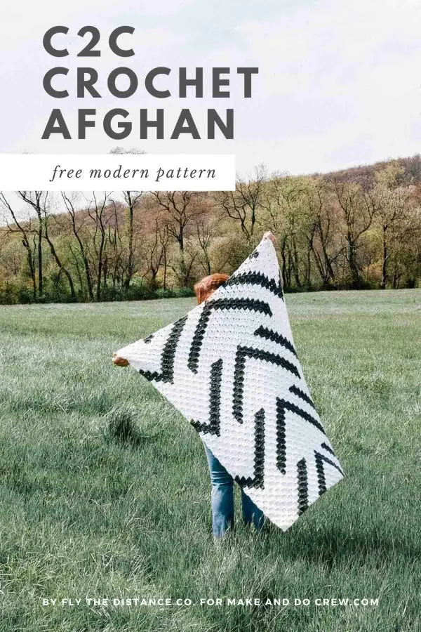 A woman holding up a geometric cheveron design c2c blanket.