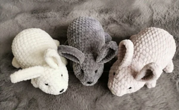 A top view of three relaistic crochet rabbit toys.