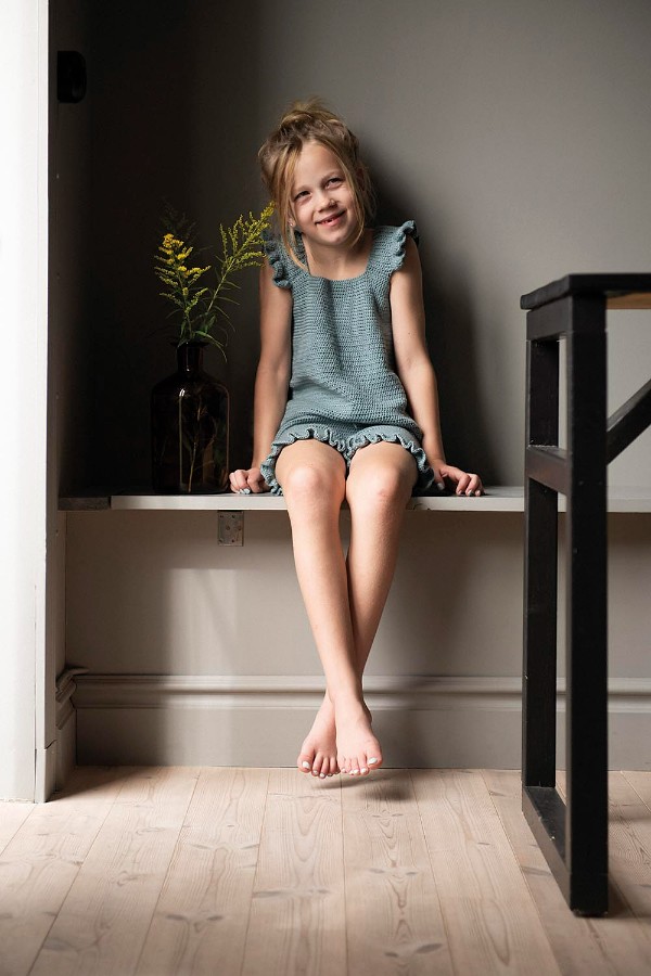 A child waeraing a soft blue crochet top with ruffle sleves.