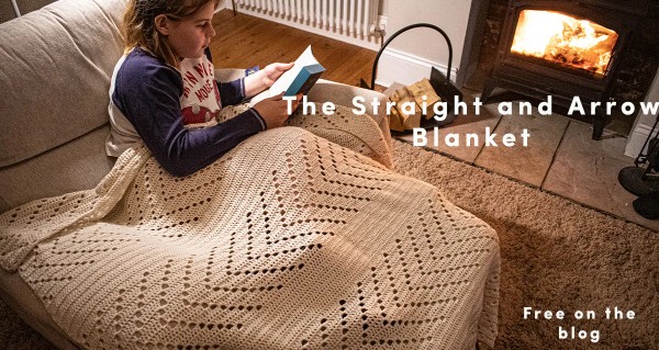 A child reading underneath a filet crochet blanket featuring arrows and solid stripes.