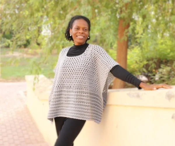 A woman wearing a casual crochet poncho.