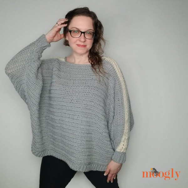A grey crochet batwing sweater with a lacy strip on the sleeves.