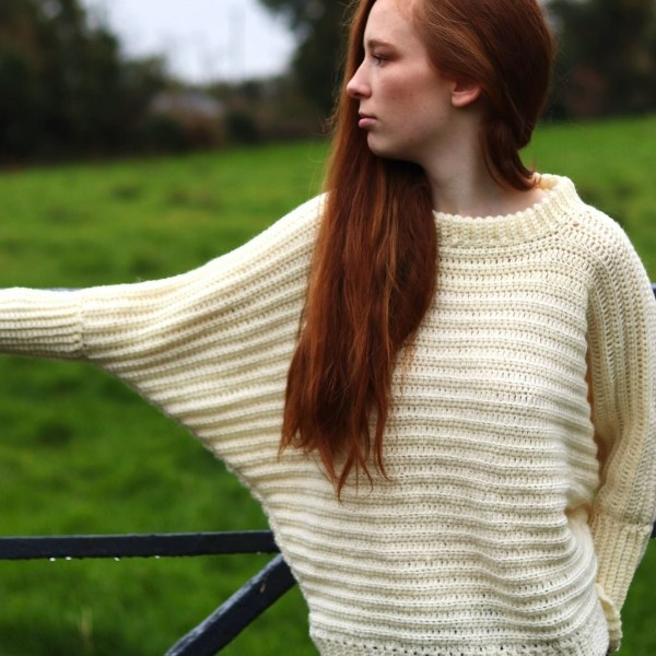 A cream-coloured crochet batwing sweater with a ribbed stitch design.