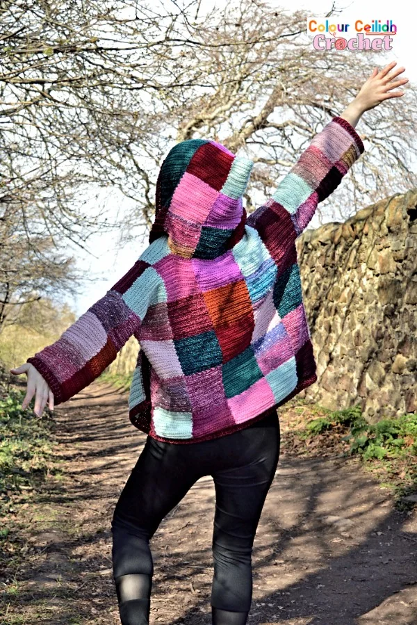 Back view of a patchwork crochet hoodie made in bright colours.