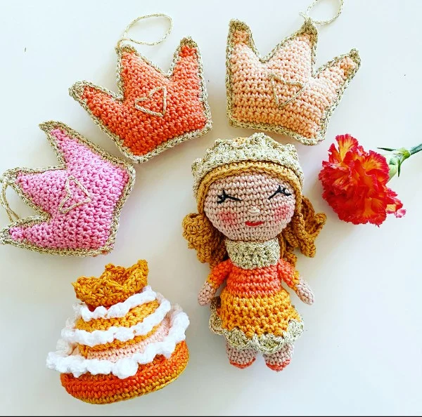 An orange crochet princess doll with a tiara.