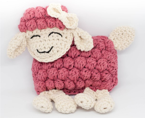 A flat-style ragdoll crochet sheep in bright pink.