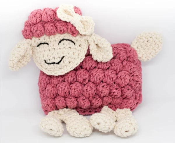 A flat-style ragdoll crochet sheep in bright pink.