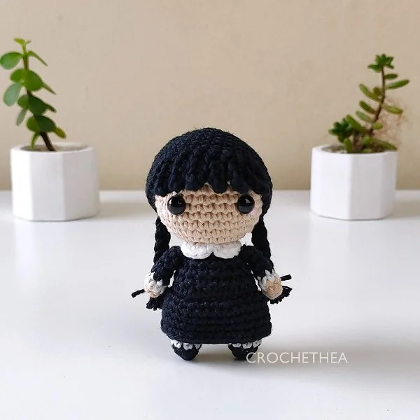 An amigurumi crochet doll of Wednesday Addams.