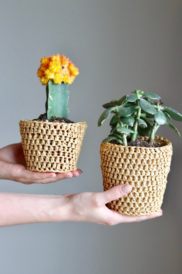 Two small crochet plant pot covers made with raffia yarn.