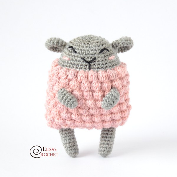 A grey crochet sheep with a pink bobble stitch fleece.