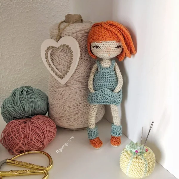 A crochet doll with orange hair and removable clothes.