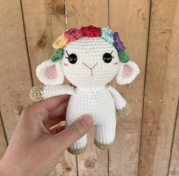 A small crochet lamb amigurumi with a flower crown.