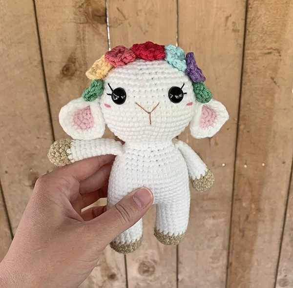 A small crochet lamb amigurumi with a flower crown.