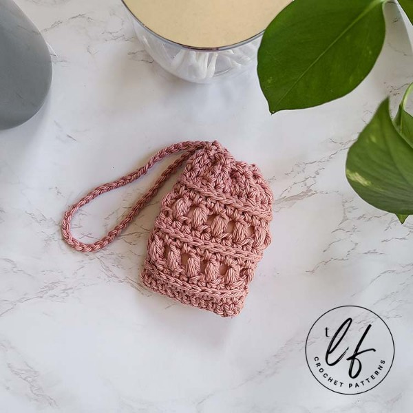 A pink crochet soap saver with puff stitch pattern.