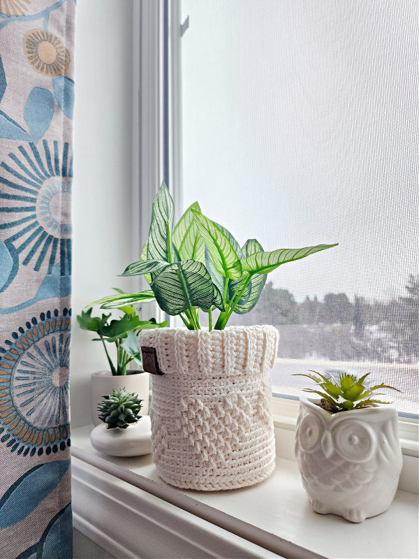 A crocheted plant pot on a windowsill.