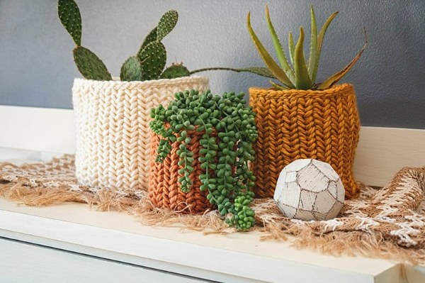 Three herringone stitch crochet plant pot covers in different colours and sizes.