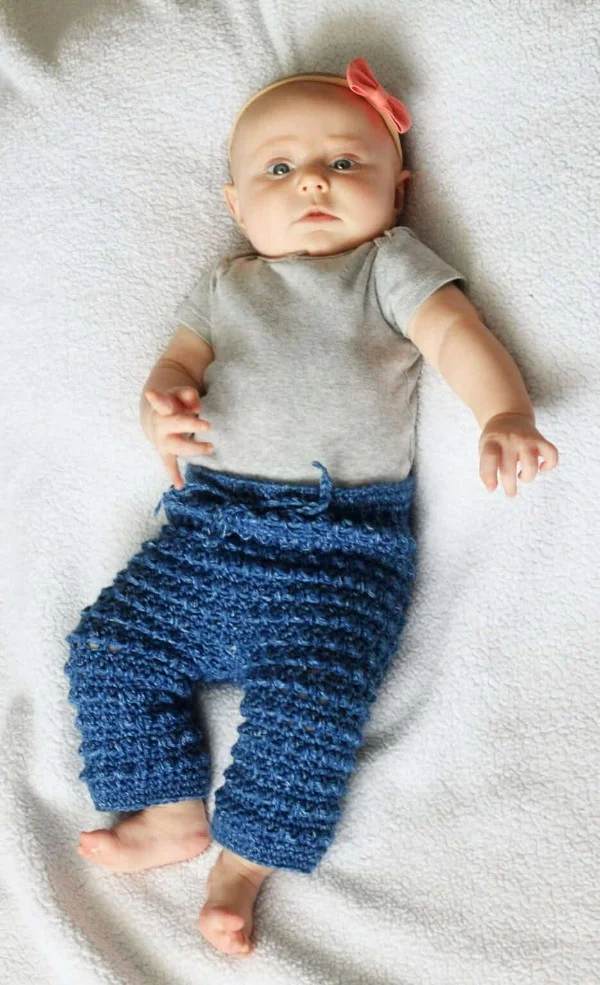 A baby wearing textured, blue crochet baby pants.