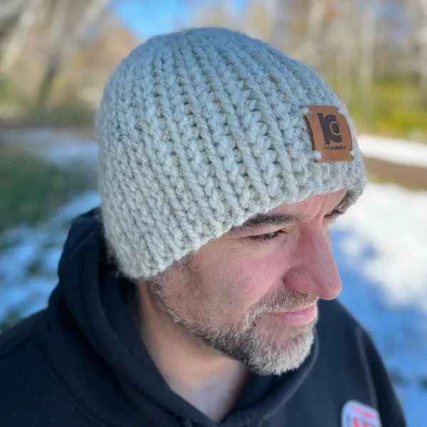 A man wearing a cream coloured, knit-look crochet beanie.