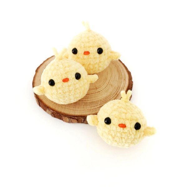 Three lemon-yellow crochet chicks made in chenille-style yarn.