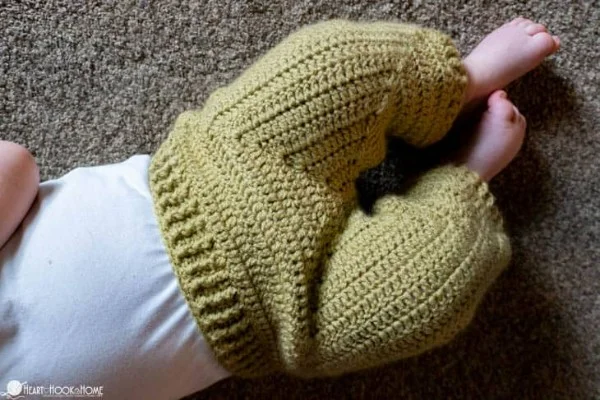 A close-up of a baby wearing crochet baby pants with a ribed waistband.