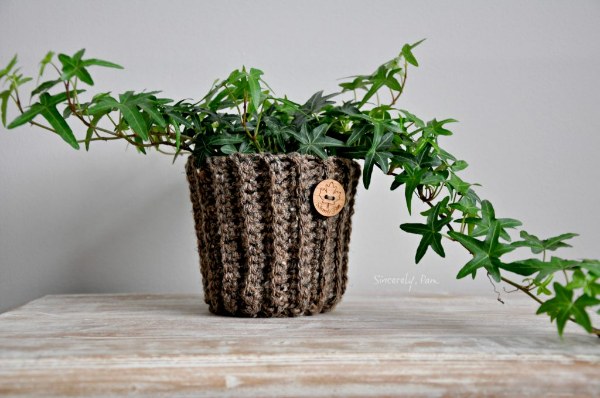 A brown, ribbed, crochet plant basket adorned with a wooden button.