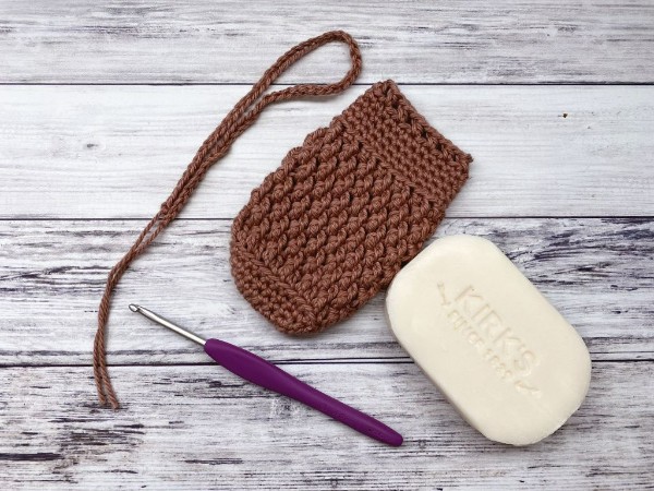 A textured crochet soap saver with a bar of soap.