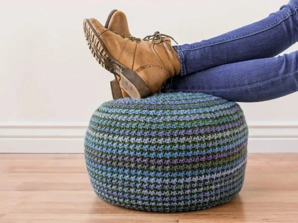 Feet resting on a blue-toned crochet pouf.