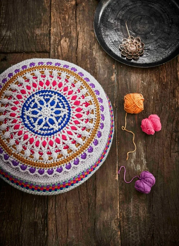 A crochet floor pouf with a multicoloured mandala design.